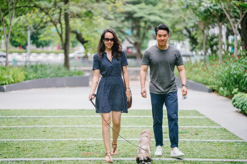A man and a woman are walking a dog in a park.